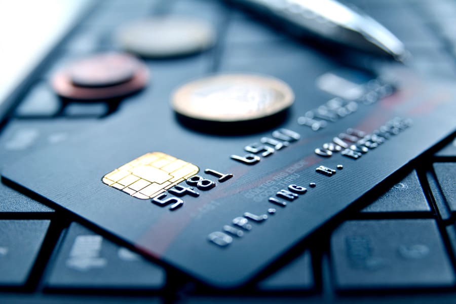 A bank card with a chip and coins on a laptop keyboard